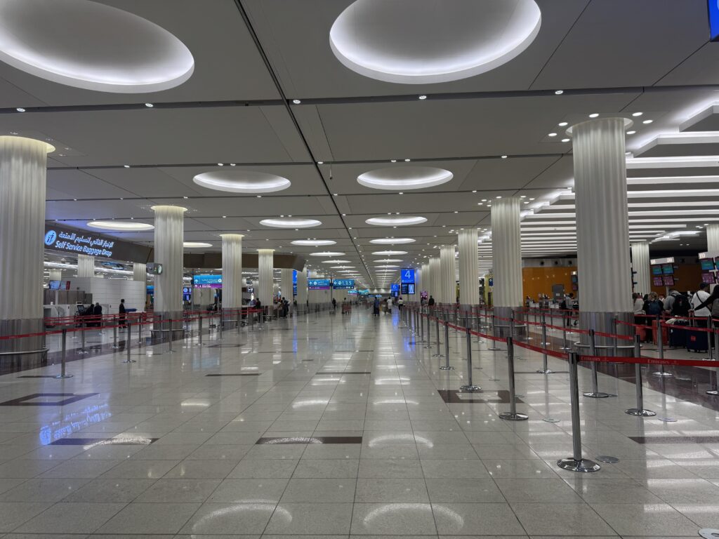 Dubai Flughafen Abflughalle mit Check-in-Bereichen, Säulen und moderner Deckenbeleuchtung