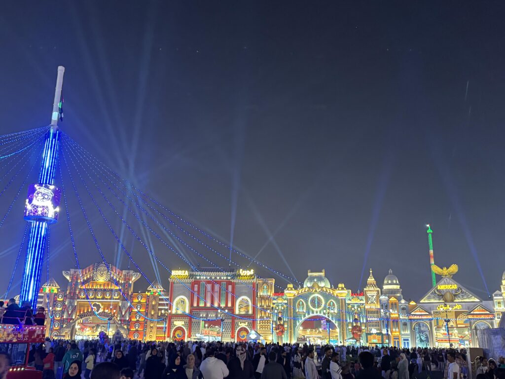 Global Village Dubai bei Nacht mit beleuchteten Länderpavillons, Besuchern und spektakulärer Lichtshow